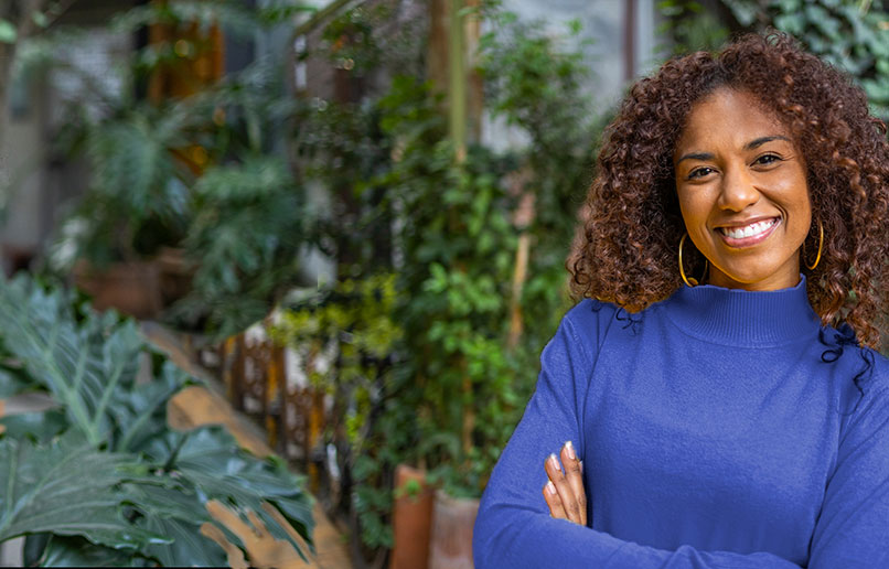 Imagem de uma mulher sorrindo em frente a uma floresta.